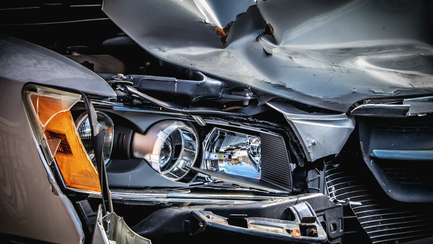 The crushed front end and broken headlight of a damaged car