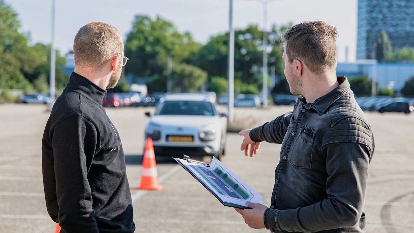 Two people inspecting a used car on a lot with paperwork on a clipboard